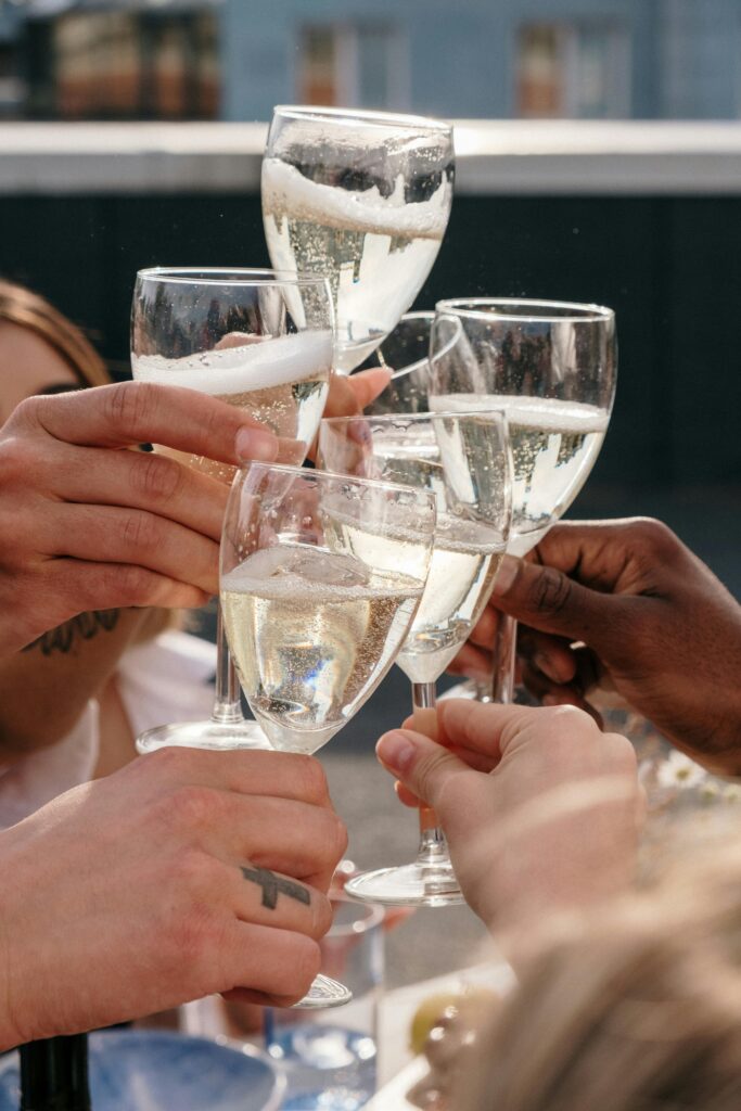 Hands raising champagne glasses in a cheerful toast at an outdoor gathering.